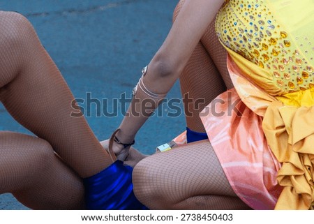 A candombe parade dancer helps her companion adjust the ornament on her legs, Montevideo, Uruguay.