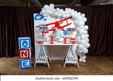 Candy bar on boy's birthday party with a lot of different candies, popcorn, beverages and big cake. Decorated in blue,red and white colors, balloons or aviation theme, indoor