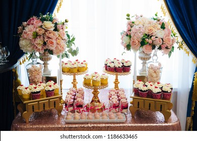 Candy bar, a table with sweets and desserts on the table. Buffet with delicious cupcakes, cake pops, biscuits, flowers.