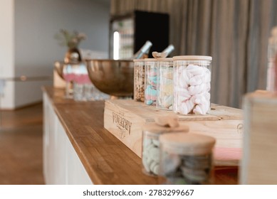 Candy buffet and drink station setup at elegant wedding reception. Stylish candy buffet and drink station with pastel sweets, champagne glasses, and elegant event decor on a wooden counter indoors. Modern wedding reception or party setup with soft natural light, Scandinavian-inspired styling, and festive atmosphere.