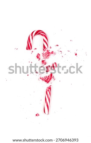 A candy cane is shattered into tiny pieces, scattering red and white fragments across a clean white background. This vibrant visual captures the essence of holiday spirit and fun.