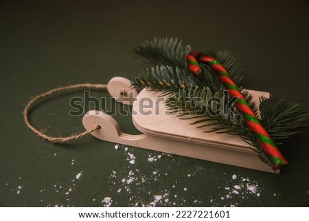 Candy canes, Christmas tree branch on wooden decorative sled.  Sweet Striped Christmas Candy on a green background. New Year and Christmas mood. Weihnachten. Happy holidays.