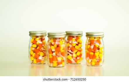 Candy Corn In 4 Mason Jars Isolated On A Solid Background