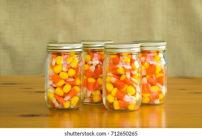 Candy Corn In 4 Mason Jars On A Wooden Table