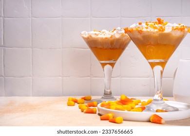 Candy corn martini drink. Sweet and salty pumpkin caramel cocktail, with candy corn sweets, copy space