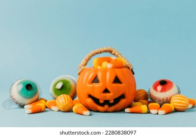 Candy corn on a blue background. Halloween concept. Bucket of Halloween pumpkin Jack-o-lantern with candy corn for halloween celebration.Pumpkin with a scary smile on his face.Candy bucket.