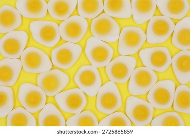 Candy in the shape of fried eggs isolated on a yellow background in top view.