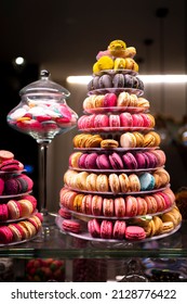 Candy shop display with colorful pyramid of French macarons biscuits at night