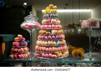 Candy shop display with colorful pyramid of French macarons biscuits at night