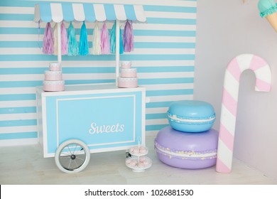 candy stall photo zone with big macaroons and a sweet cone and blue and white striped background