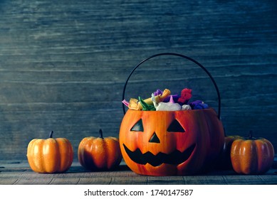 The Candy That The Children Received As A Gift Put In A Pumpkin-shaped Basket Which Had A Cool Face Decorate With Small Pumpkin On Old Wood Table, Halloween Party Concept