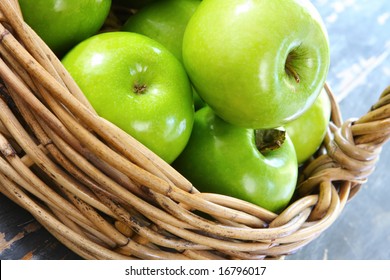 Cane Basket Of Granny Smith Apples, On Rustic Wooden Table.