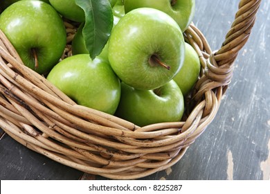 Cane Basket Of Green Granny Smith Apples, On Rustic Tabletop.