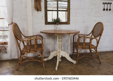 Cane Furniture Set Of Two Chairs And A Coffee Table Against A White Wall 