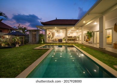 Canggu, Bali, Indonesia, 20 October 2019. White modern luxurious mansion interior in modern villa. Tropical villa view with garden, swimming pool and open living room at sunset