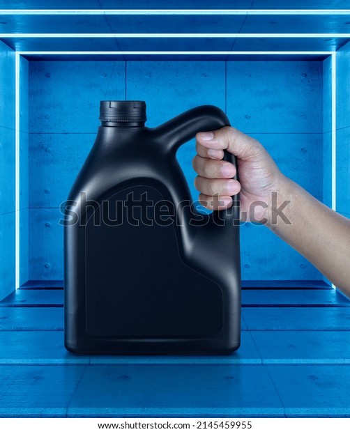 A canister with engine oil in a\
hand. on Abstract blue room interior with White neon\
lamps