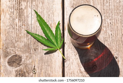 Cannabis Beer On A Picnic Table Wood Surface, Outside On A Warm Sunny Day. Cannabis Leaf. A New Alternative To Alcoholic Beverages.