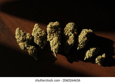 Cannabis buds in row on dark wooden background. Top view, close-up of hemp dried flowers. Marijuana drying and curing. Weed stuff, legal CBD recreational use. Sort LSD.