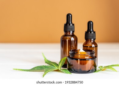 Cannabis Face Cream Or Serum Or Oil Dropper Concept. Natural Cosmetic. CBD Oil, THC Tincture And Hemp Leaves On A Wooden Background.