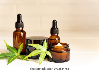 Cannabis Face Cream Or Serum Or Oil Dropper Concept. Natural Cosmetic. CBD Oil, THC Tincture And Hemp Leaves On A Wooden Background.