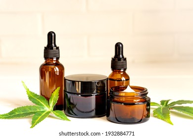 Cannabis Face Cream Or Serum Or Oil Dropper Concept. Natural Cosmetic. CBD Oil, THC Tincture And Hemp Leaves On A Wooden Background.