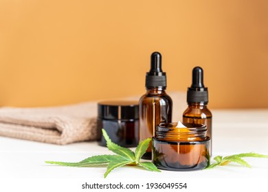 Cannabis Face Cream Or Serum Or Oil Dropper Concept. Natural Cosmetic. CBD Oil, THC Tincture And Hemp Leaves On A Wooden Background.