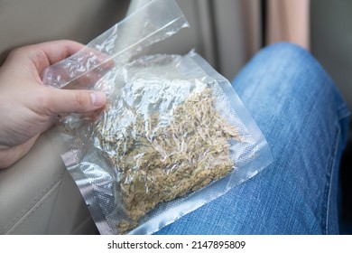 Cannabis In Grinder Joint And A Packet Of Weed On A Car Background Close Up Marijuana Bud Flowers Of Cannabis. Grinder And Shredded