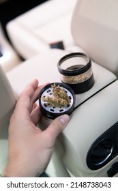 Cannabis In Grinder Joint And A Packet Of Weed On A Car Background Close Up Marijuana Bud Flowers Of Cannabis. Grinder And Shredded