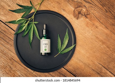 Cannabs Medical Product, CBD Oil, With Hemp Leaves On A Black Dish On A Wooden Table. Flat Lay. Mockup Copy Spase