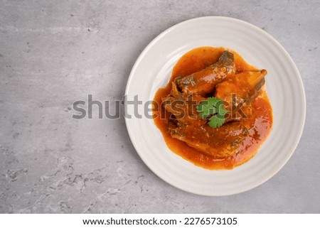 Canned fish. Mackerel in tomato sauce in a white plate on a concrete table.