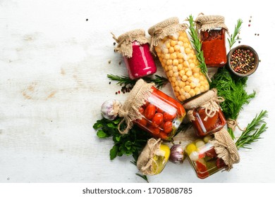 Canned Food In Glass Jars On White Wooden Background. Pickled Vegetables And Mushrooms.