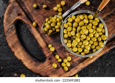 Canned green peas on a cutting board. On a black background. High quality photo