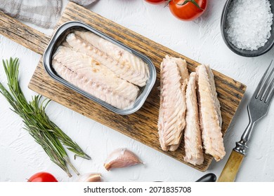 Canned Mackerel Fillets in Tin set, on wooden cutting board, on white background with herbs and ingredients, top view flat lay