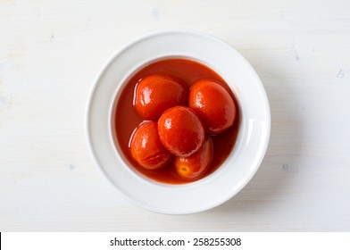 Canned tomatoes in juice in a white plate top view