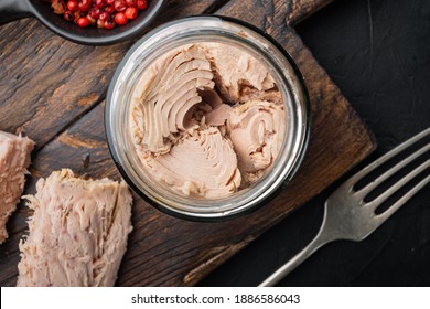 Canned tuna fillet meat in olive oil, on black background, flat lay