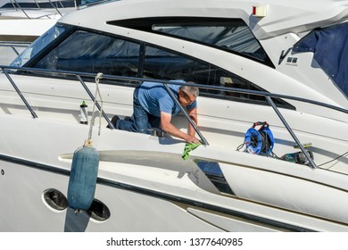 CANNES, FRANCE - APRIL 2019: Person polishing the paintwork on a superyacht in Cannes harbour preparing it for the charter season