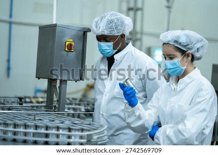 Canning supervisor observes empty cans on a conveyor during a production audit to ensure hygiene and quality standards in a food factory.