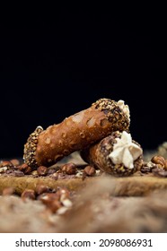 Cannoli, deep fried Italian delicious pastry tubes with a sweet ricotta cheese, chocolate chips and hazelnuts served on a wooden board