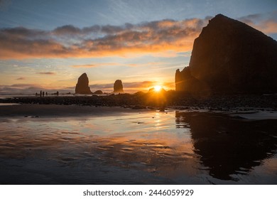 Cannon Beach, beach sunset, Oregon, pnw, pacific northwest, USA, famous beach, coastal landscape, reflection, beach rocks, golden hour on the coast, warm light, sunshine, holidays - Powered by Shutterstock