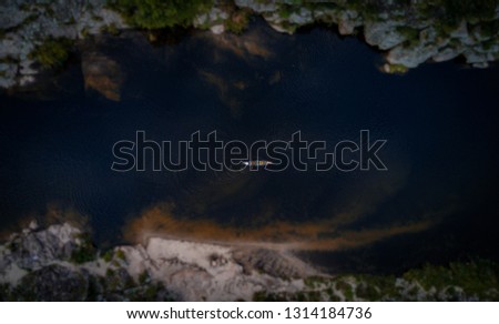 Canoe going through the river that is located between mountains. Aerial view from a drone. overhead shot.