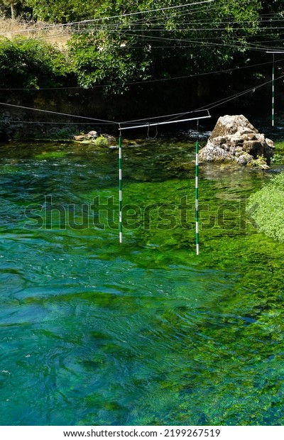 Canoe Kayak\
Slalom. Green gates. The emerald, crystal-clear Sorgue river,\
Fontaine de Vaucluse, France. Famous\
place.