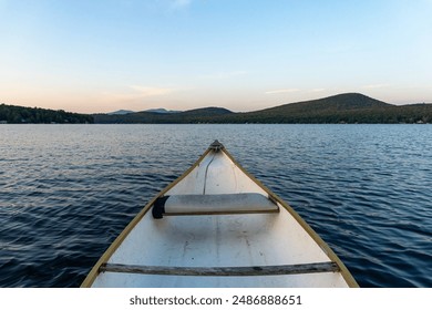 Canoe in a lake surrounded by mountains at sunset.  - Powered by Shutterstock