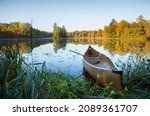 Canoe with paddle on shore of beautiful lake with island in northern Minnesota at sunrise