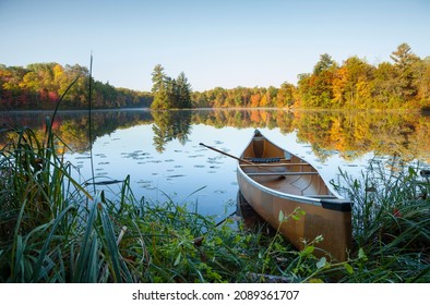 Canoe with paddle on shore of beautiful lake with island in northern Minnesota at sunrise