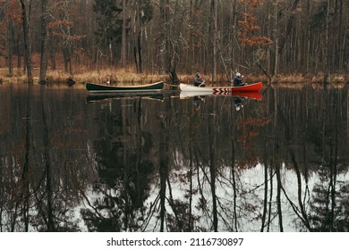 Canoe Paddling Lifestyle: Two Persons In A Boat Towing An Empty Vessel In The Forest Lake. Beautiful Autumn Landscape With People Paddling Canadian Canoe