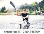 Canoeist man sitting in canoe paddling, in water. Concept of canoeing as dynamic and adventurous sport. Rear view, sportman looking at water surface, paddling