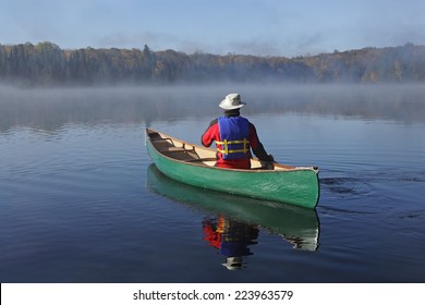 Canoeist Paddling a Green Canoe on a Misty Autumn Lake - Ontario, Canada - Powered by Shutterstock