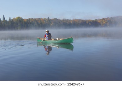 Canoeist Paddling a Green Canoe on a Misty Autumn Lake - Ontario, Canada - Powered by Shutterstock