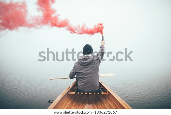 Canoeist using smoke bomb to signal his position on\
the foggy lake