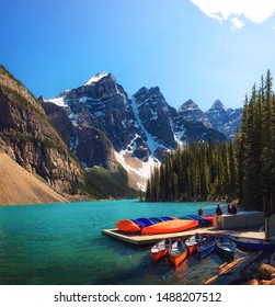Canoes on a jetty at Moraine lake in Banff National Park, Alberta, Canada, with snow-covered peaks of canadian Rocky Mountains in the background.